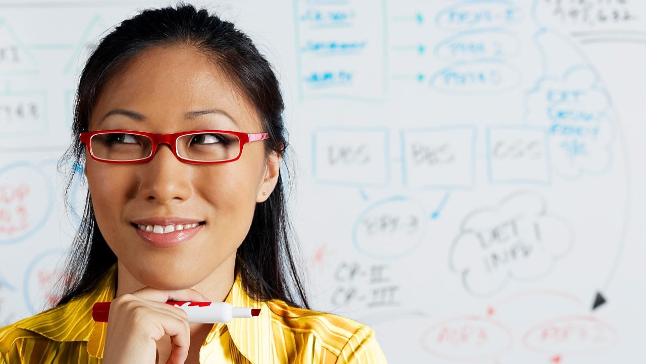 Close up of Asian businesswoman smiling in front of whiteboard
