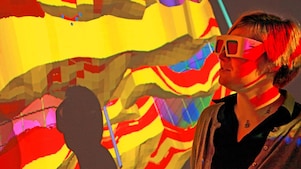 A woman with special goggles examines a 3D wall projection of a geological map