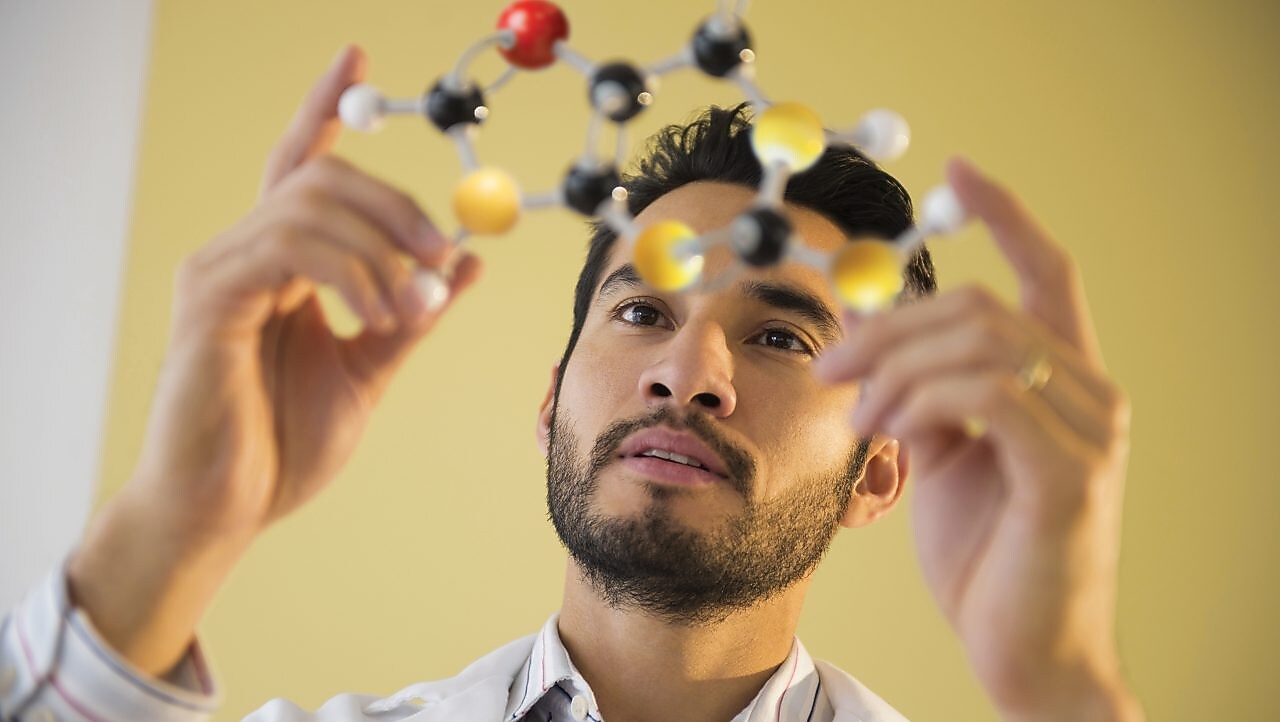 Young man examining molecular model.