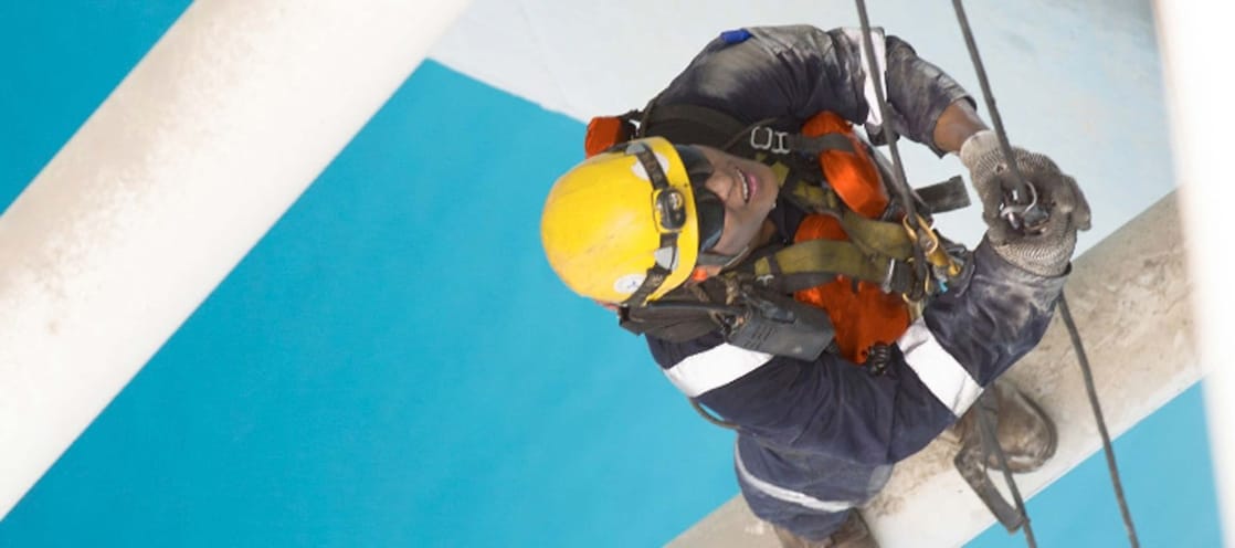 Aerial view of man working in safety gear climbing scaffolding